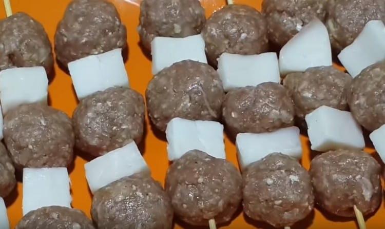 Na dřevěných špejlích navlékáme masové kuličky a kousky tlustého ocasu.