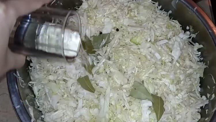 Agregue la hoja de laurel, los granos de pimienta y el vinagre a la col.