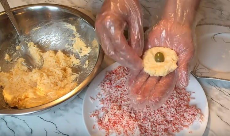 À partir de la masse de fromage et d'œuf, nous formons un gâteau et plaçons l'olive au centre.