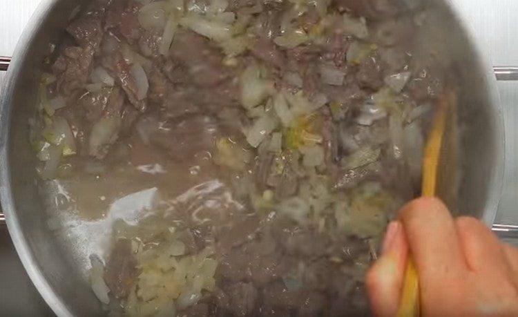 Agregue las cebollas y el ajo a la carne.