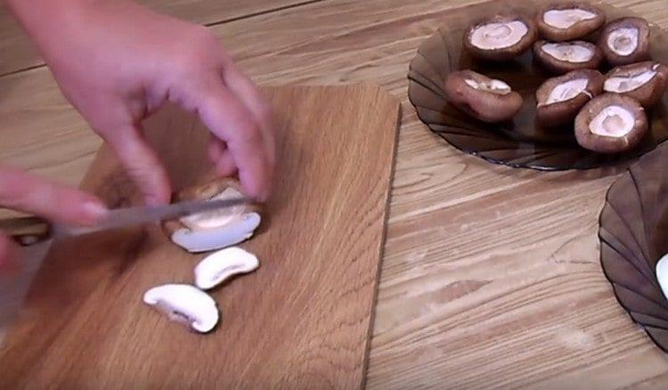 Capacele de ciuperci tăiate în farfurii.