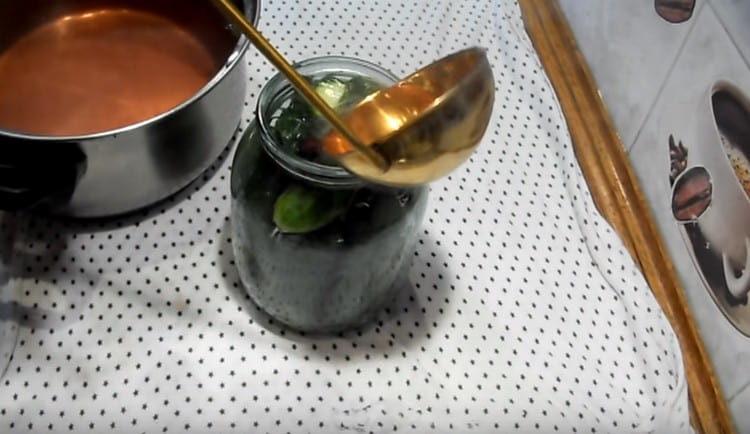 La marinade bouillie verse des pots de concombres auxquels elle ajoute du vinaigre.