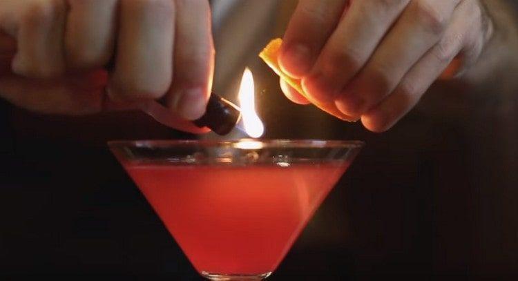 Direkt über dem Glas die Orangenschale leicht anbrennen.