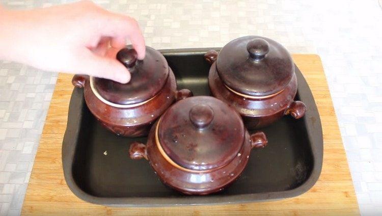 Покриваме съдовете с капаци, слагаме върху лист за печене и слагаме във фурната.