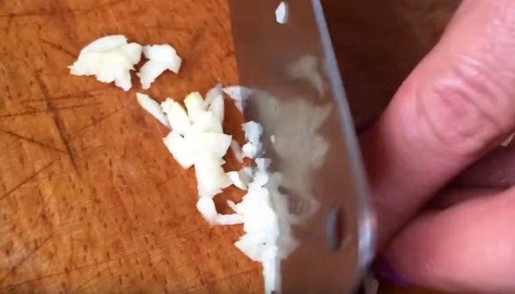 Slib hvidløg med en kniv.