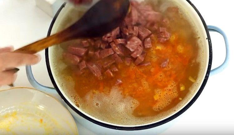 Întindem cârnați într-o cratiță cu supă.